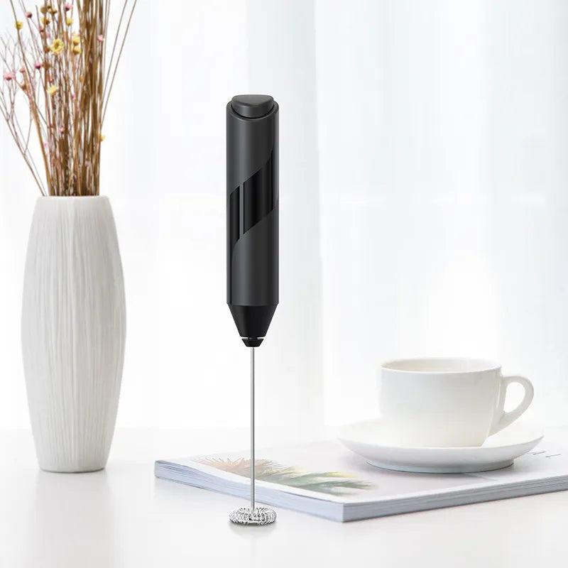 Black handheld device on a white surface with a cup and vase in the background