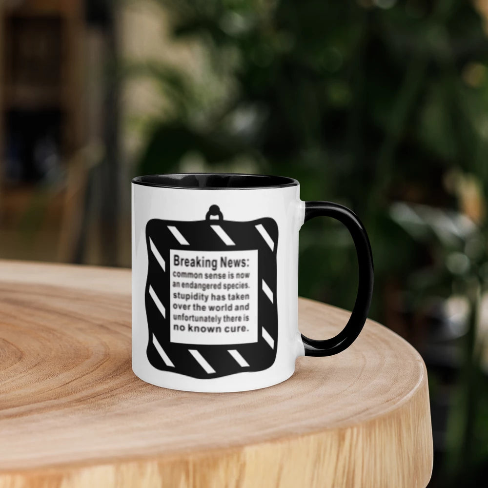 Mug with black interior and handle, featuring a warning sign design on a wooden surface with a blurred background.