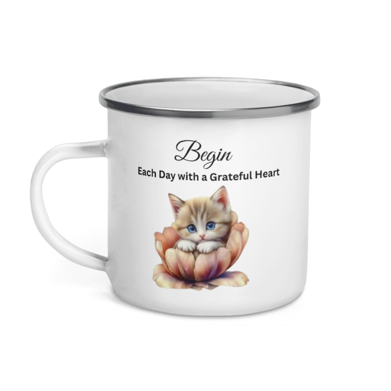 A white enamel-style mug with a silver rim, featuring a printed design of a small orange tabby kitten sitting in a peach flower with the text 'Begin Each Day with a Grateful Heart'.