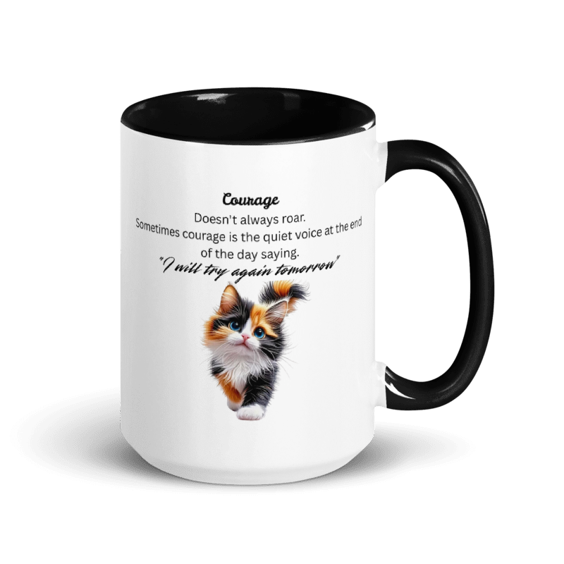 A white ceramic mug with a black interior and black handle, featuring a printed design of a small calico kitten and the text 'Courage' with a quote underneath.