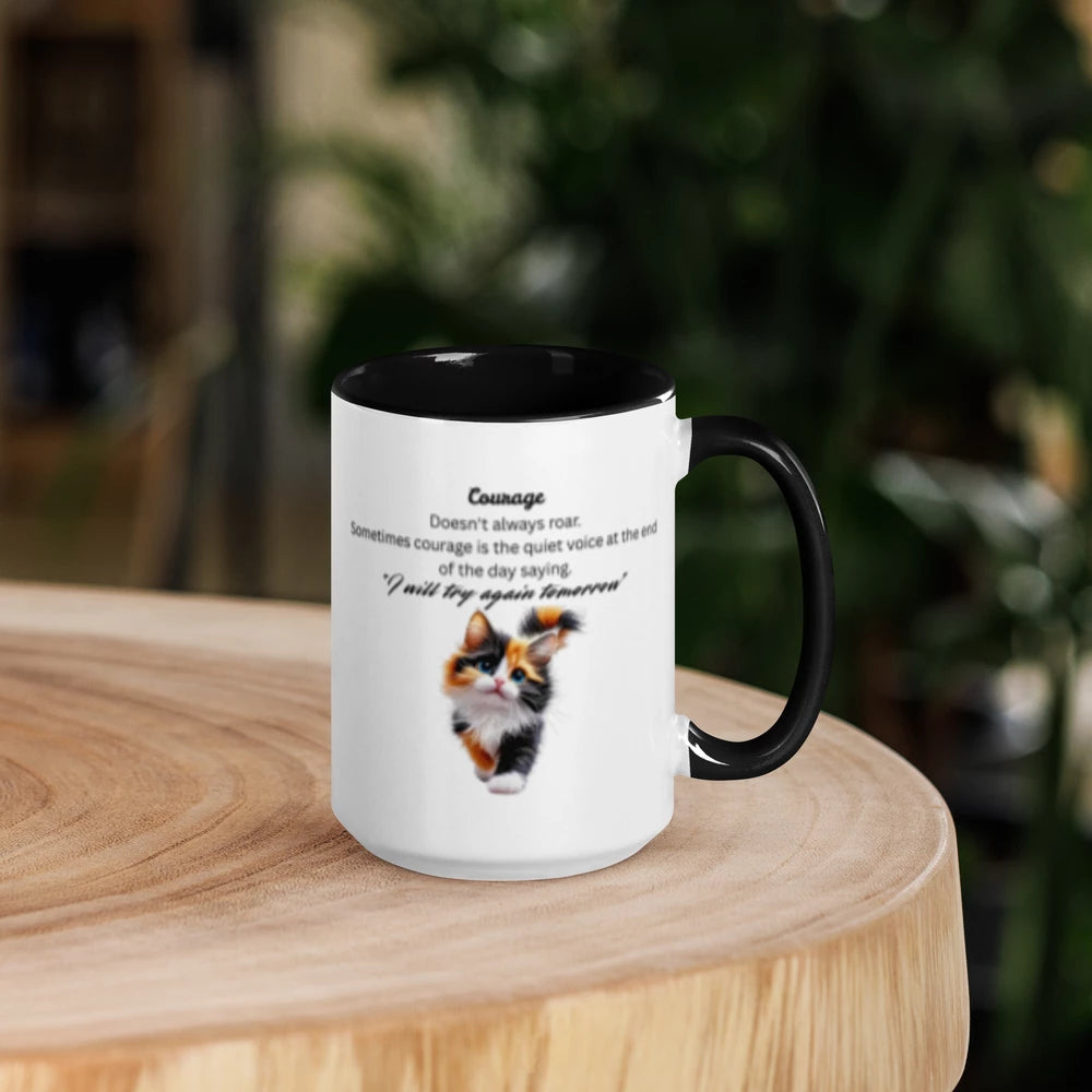 A white ceramic mug with a black interior and black handle, featuring a printed quote and a calico cat illustration, displayed on a round wooden surface with a blurred green background.