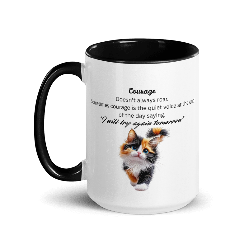 A white ceramic mug with a black handle and black interior, featuring a printed definition of courage and a small calico kitten illustration on the front.