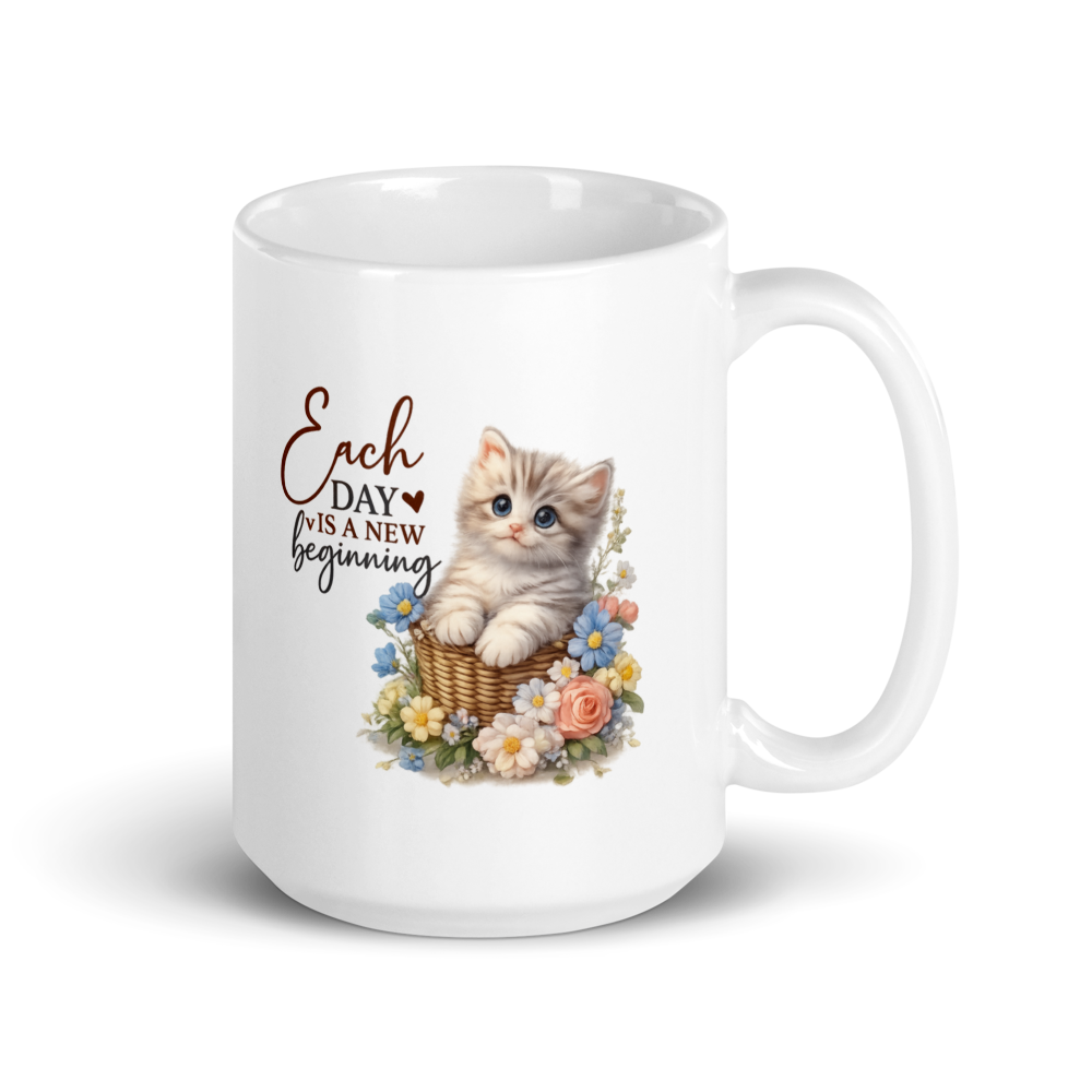 A white ceramic mug with a printed graphic of a cute tabby kitten sitting in a basket surrounded by colorful flowers, next to the text 'Each DAY is a NEW beginning' in brown and black script.