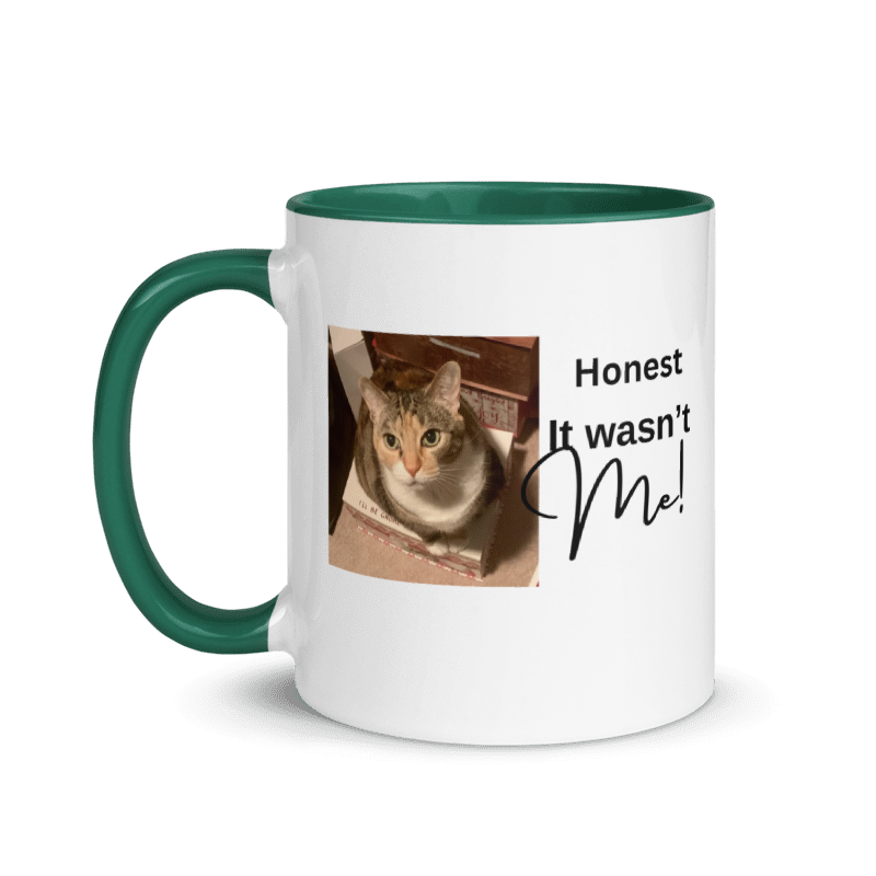 A white ceramic mug with a dark green handle and interior rim, featuring a printed photo of a cat and the text 'Honest It wasn't Me!' on the front.