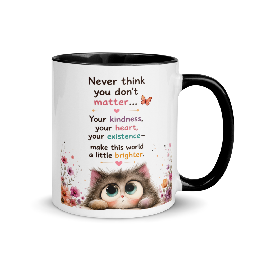 A white ceramic mug with a black interior and black handle, featuring a printed message about kindness and heart, alongside a cute cartoon kitten illustration and floral accents.