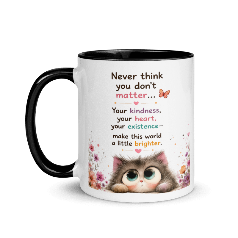 A white ceramic mug with a black handle and black interior, featuring a printed message about kindness and a cute cartoon kitten with floral accents.