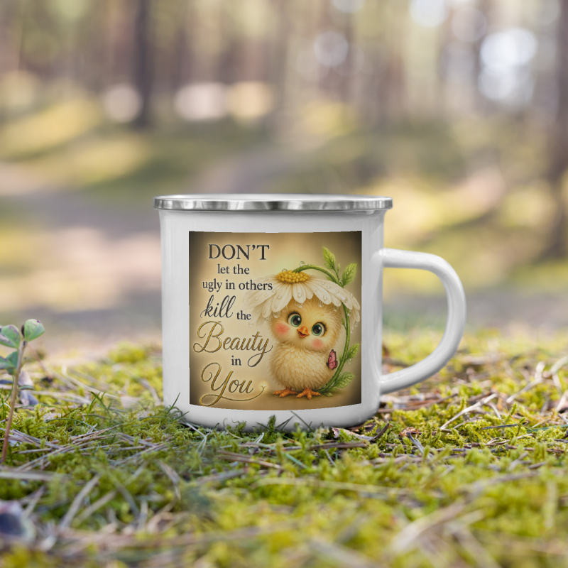 A white enamel-style mug with a silver rim sits on green moss in a blurred forest setting. The mug features a printed design of a cute yellow chick under a daisy with the text, 'DON'T let the ugly in others kill the Beauty in You'.