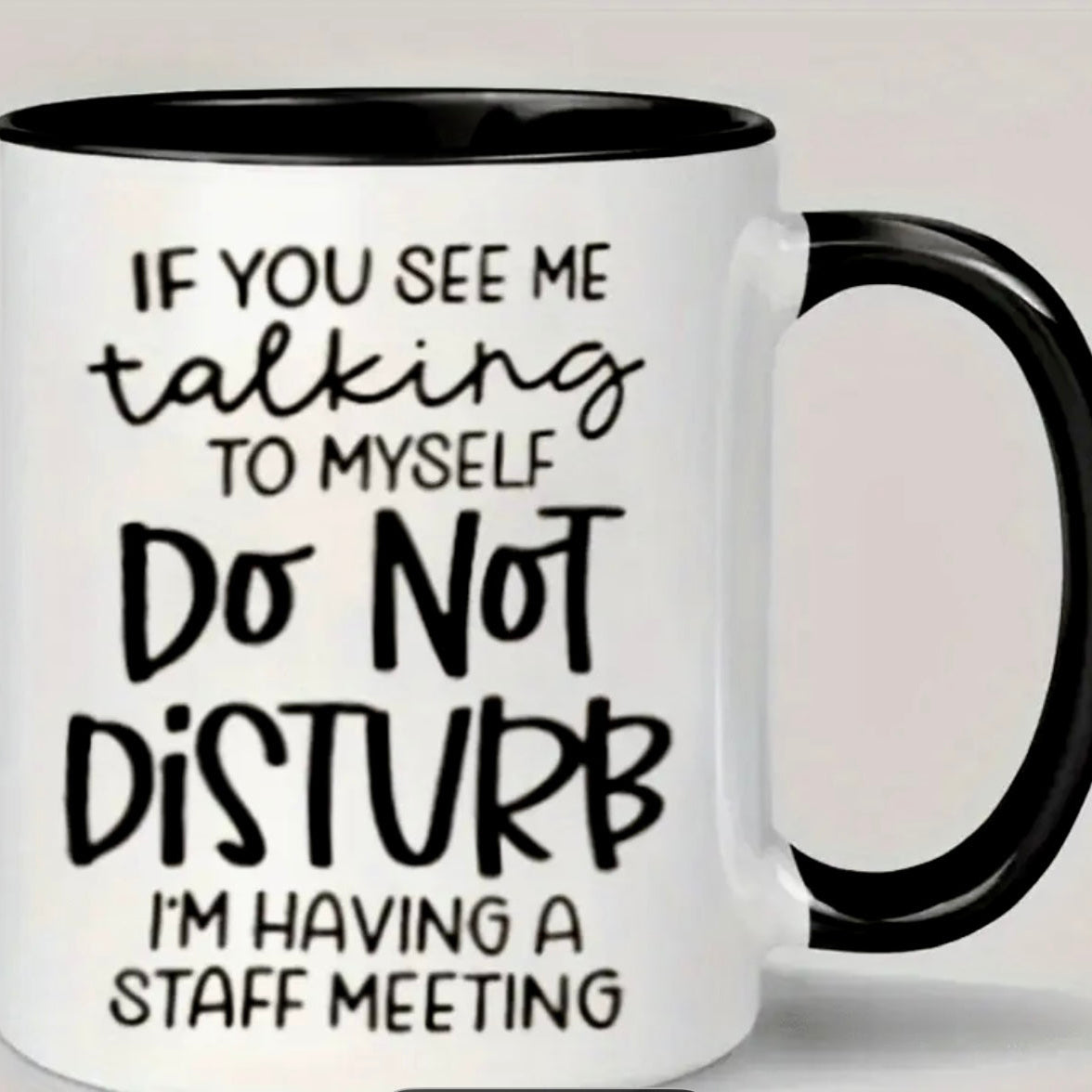 White mug with black interior and handle, featuring humorous text 
(DO NOT DISTURB...) on a light gray background