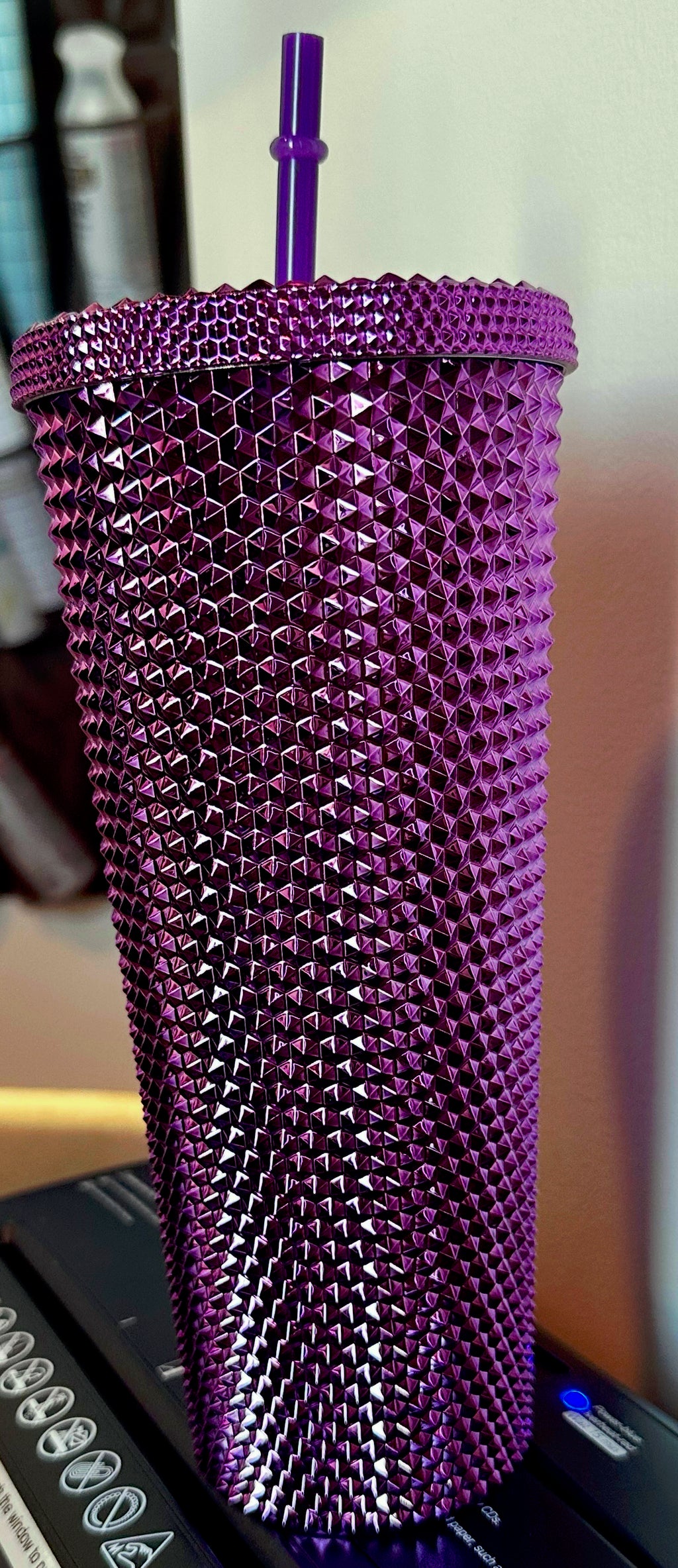 Purple textured tumbler with a straw on a blurred background