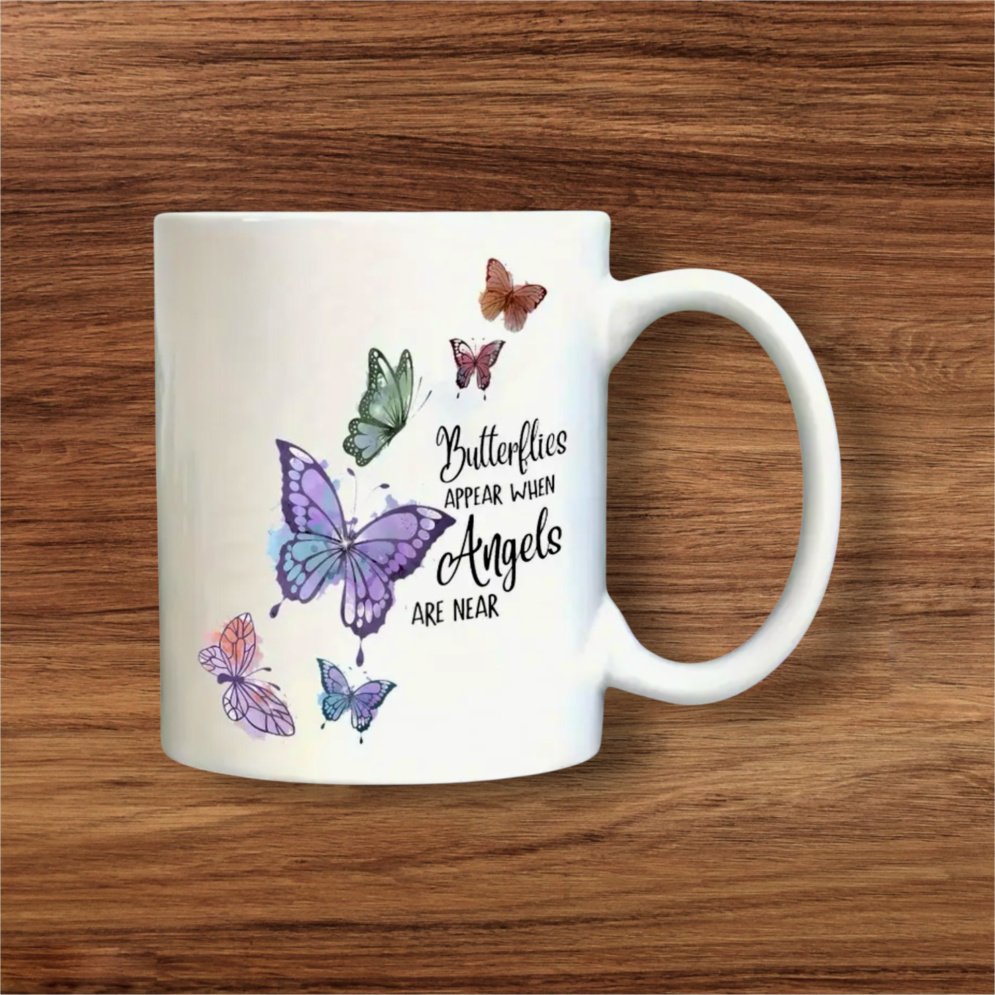 White mug with butterfly designs and text on a wooden surface