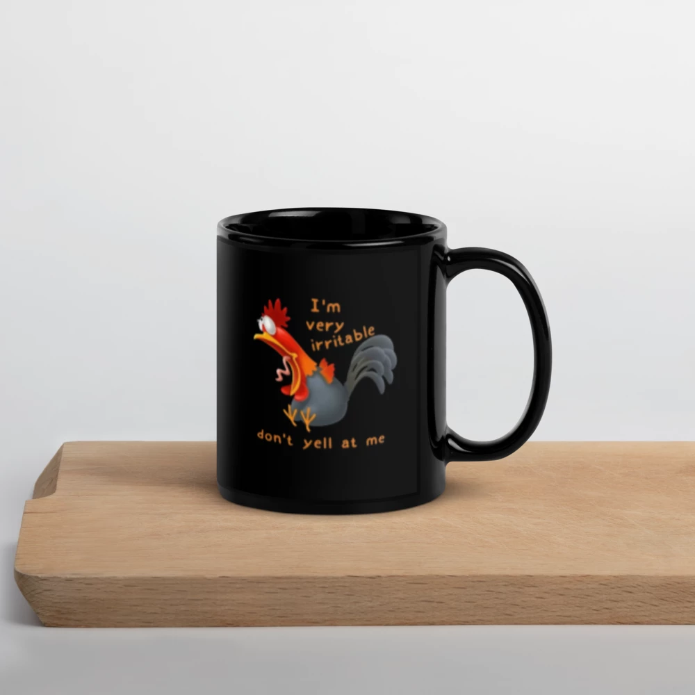 Black mug with a rooster design and text on a wooden surface