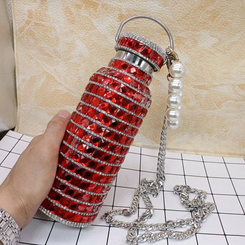 Decorative red water bottle with silver chain and pearl charm on a checkered surface.