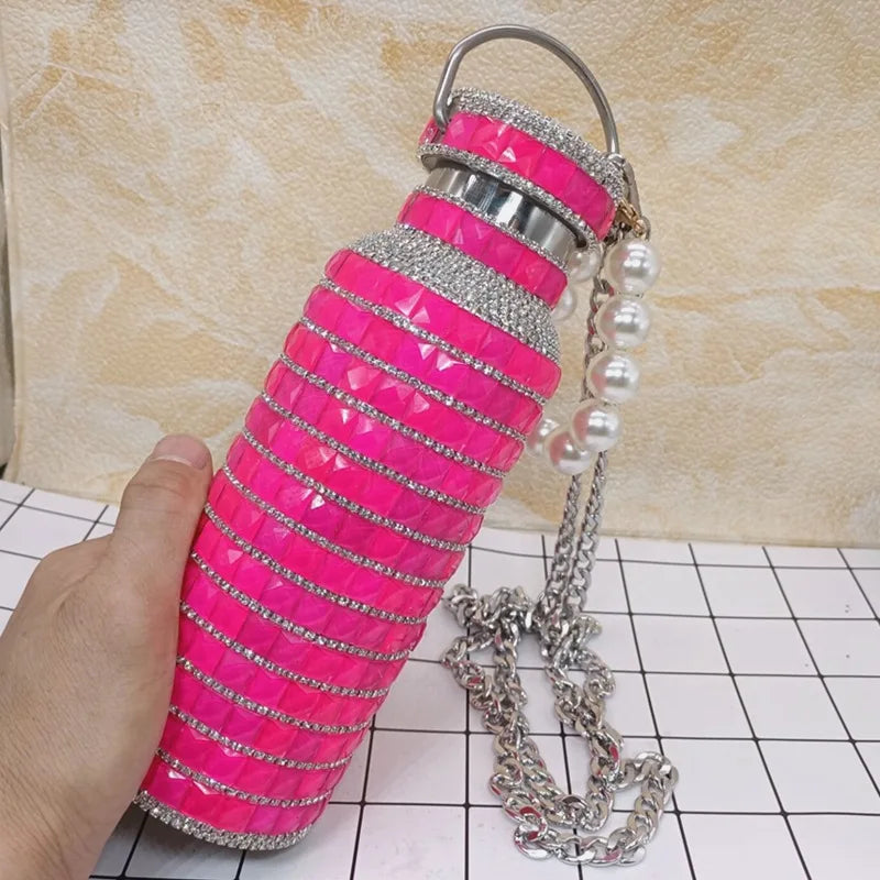 Hot pink water bottle with silver chain and pearls on a tiled floor.