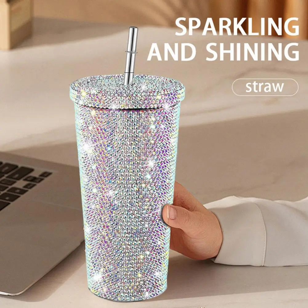 Sparkling AB tumbler with a straw held by a hand on a desk with a laptop.