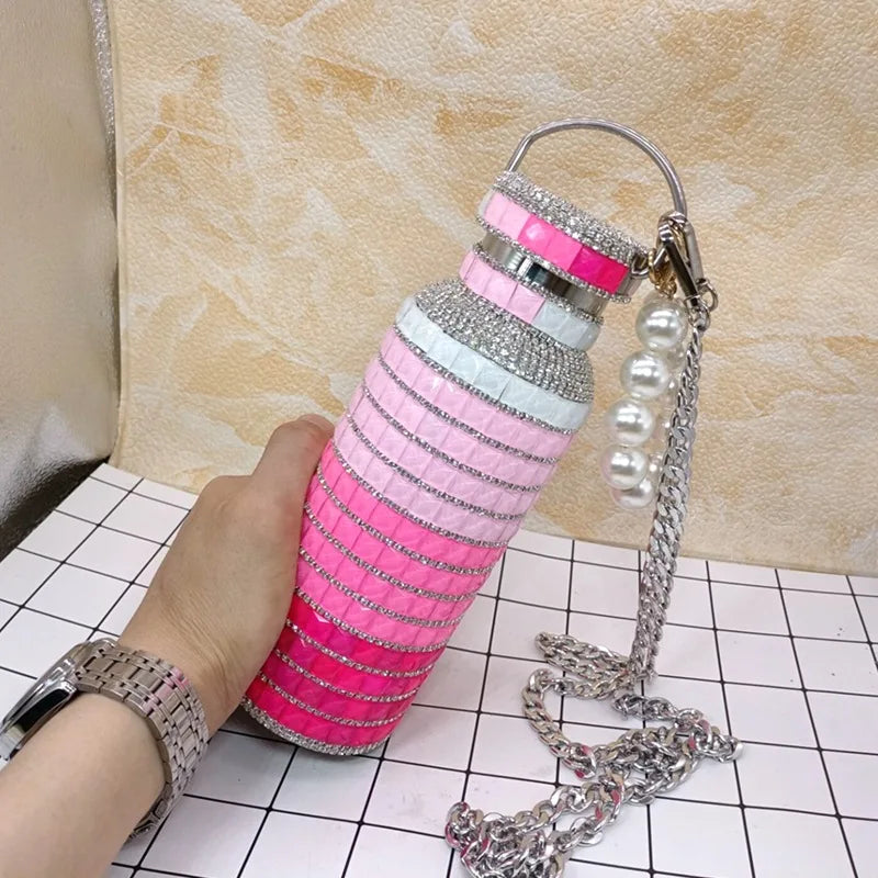 Decorative water bottle with rhinestones/gemstones pink gradient design on a tiled floor.