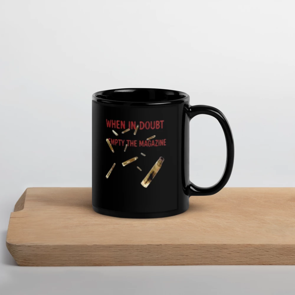 Black mug with red and gold text and graphics on a wooden surface