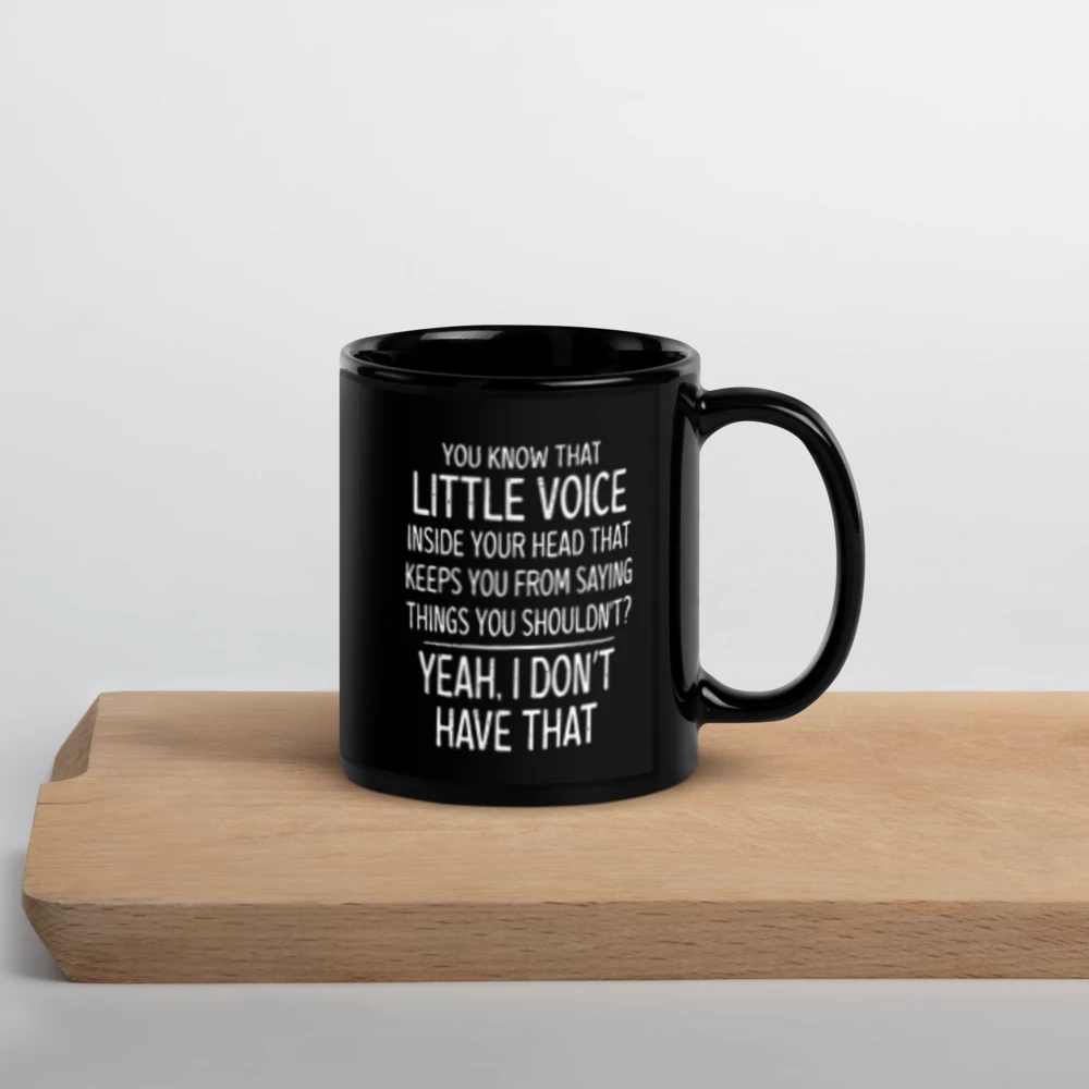 Black mug with humorous text on a wooden surface